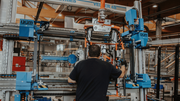Opérateur pilotant une machine de fabrication de menuiseries dans l'atelier